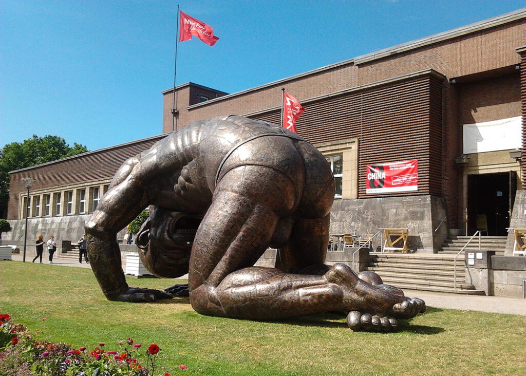 Bending by Yue Minjun, exhibited in front of the NRW-Forum on the occasion of the mega-exhibition China 8 in 2015.